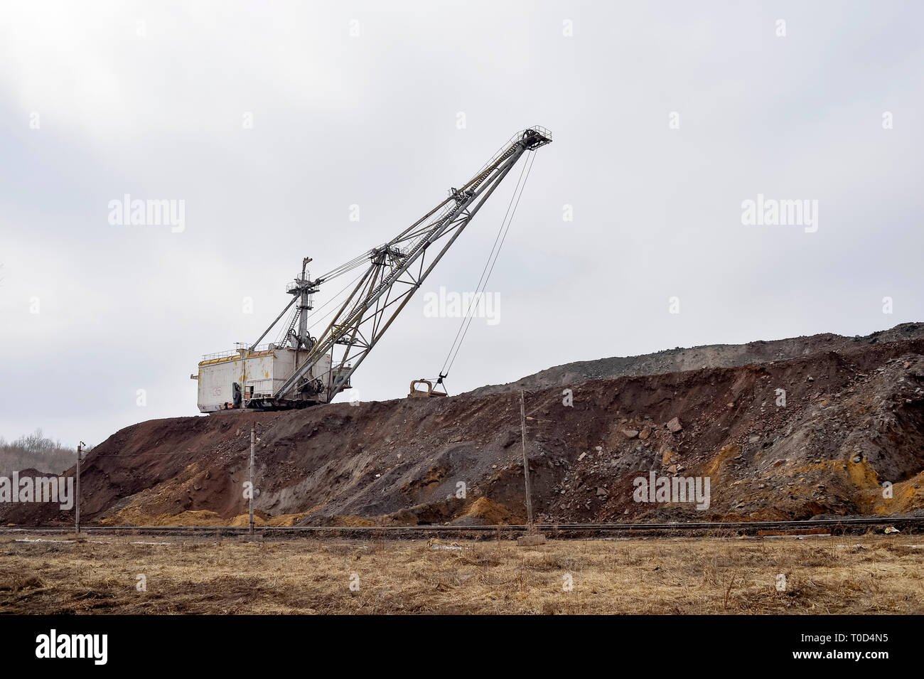 Grande escavatore a piedi in previsione del materiale rotabile il trasporto di sovraccaricare per lo stoccaggio in discariche. Paesaggio industriale dopo la distruzione di n Foto Stock