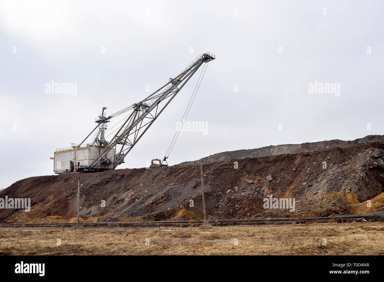 Grande escavatore a piedi in previsione del materiale rotabile il trasporto di sovraccaricare per lo stoccaggio in discariche. Paesaggio industriale dopo la distruzione di n Foto Stock