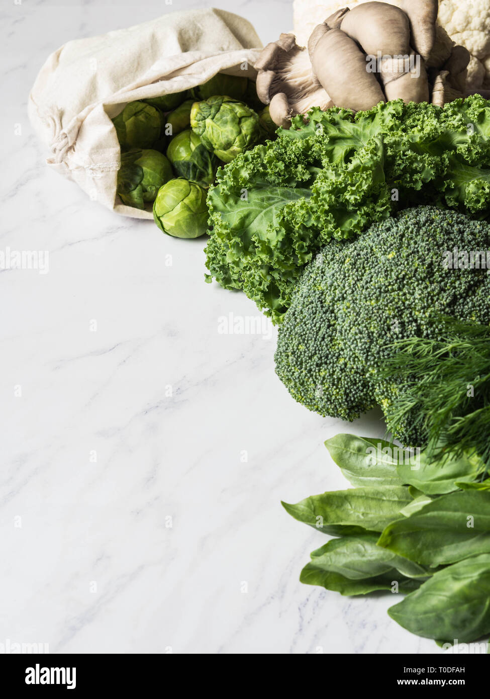 Verde di sani ingredienti vegan per la cottura. Vari verde pulito le verdure e le erbe su sfondo marmo. Prodotti dal mercato senza materia plastica. Foto Stock