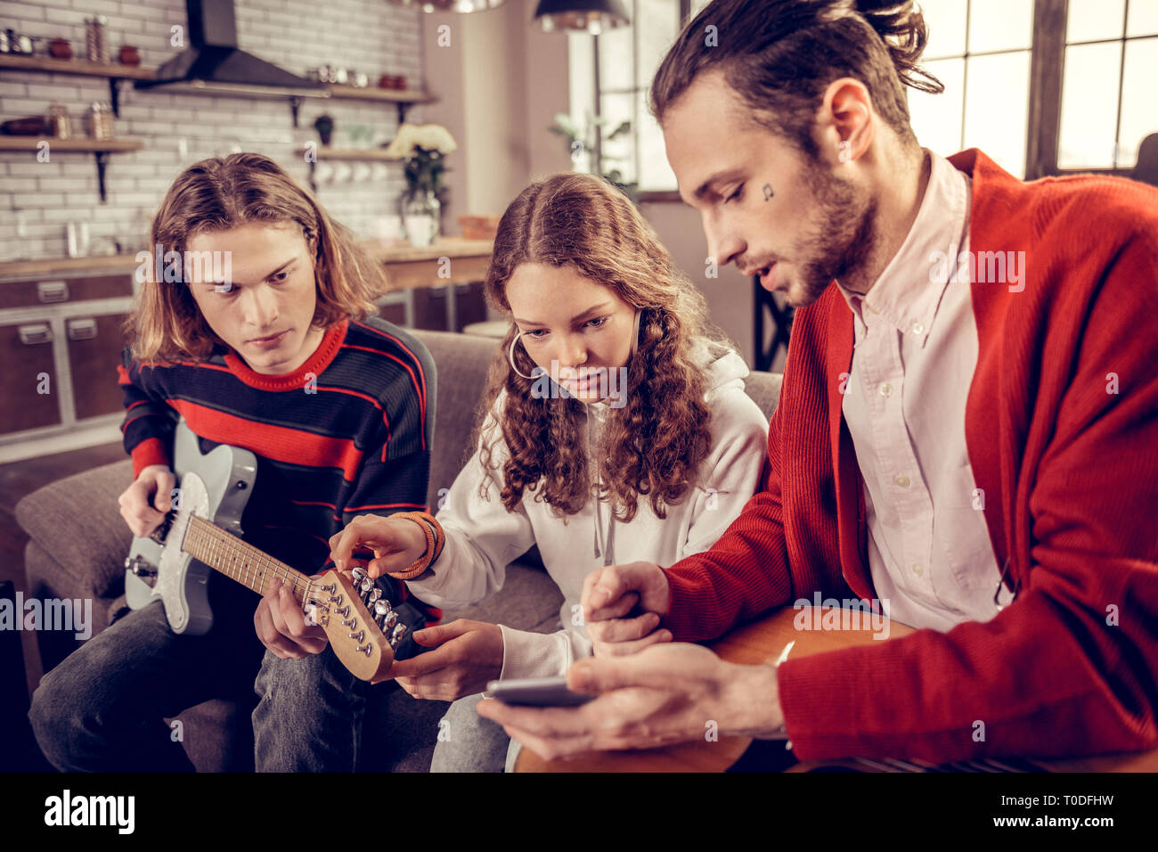 Insegnante di chitarra con poco tatuaggio sul suo volto insegnamento del fratello e sorella Foto Stock