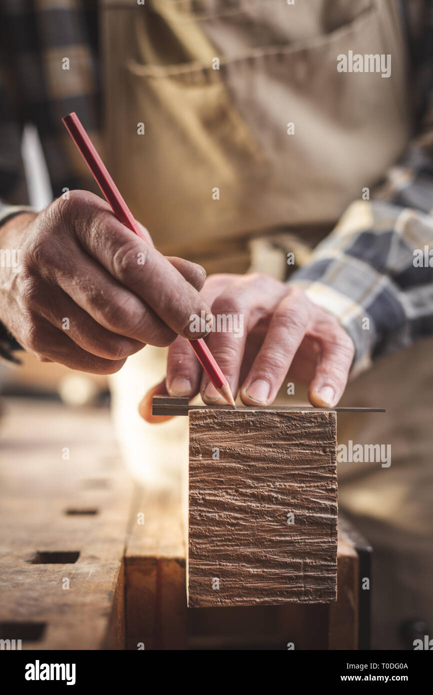 Artigiano segnando un pezzo di legno con una matita Foto Stock