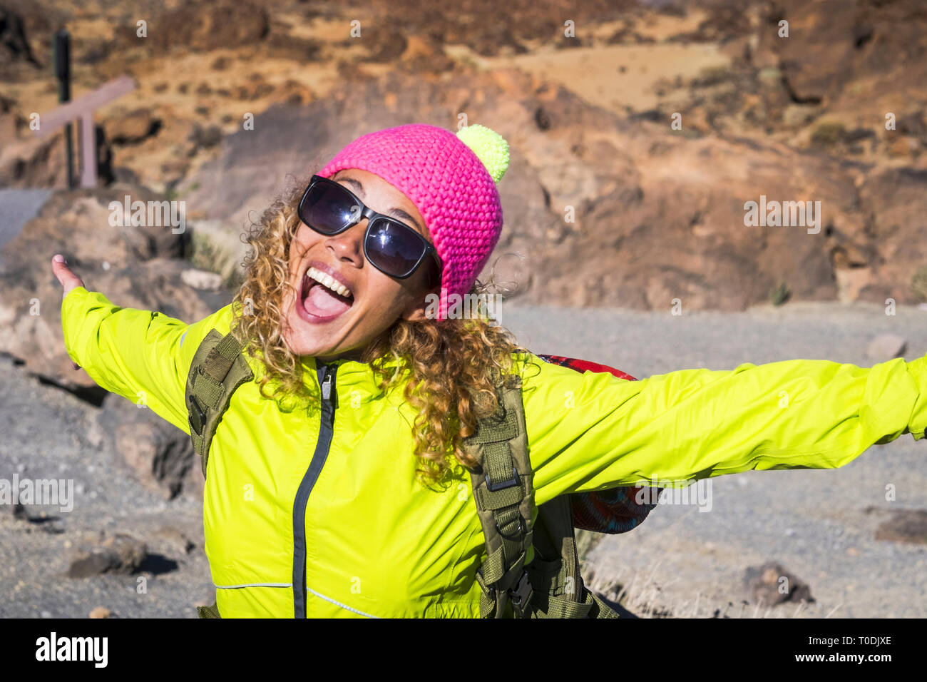 Giovane bella donna ridere e sorridere con gioiosa e a braccia aperte godendo l'alternativa vacanza escursionistica in montagna all'aperto in estate - giornata di sole un Foto Stock