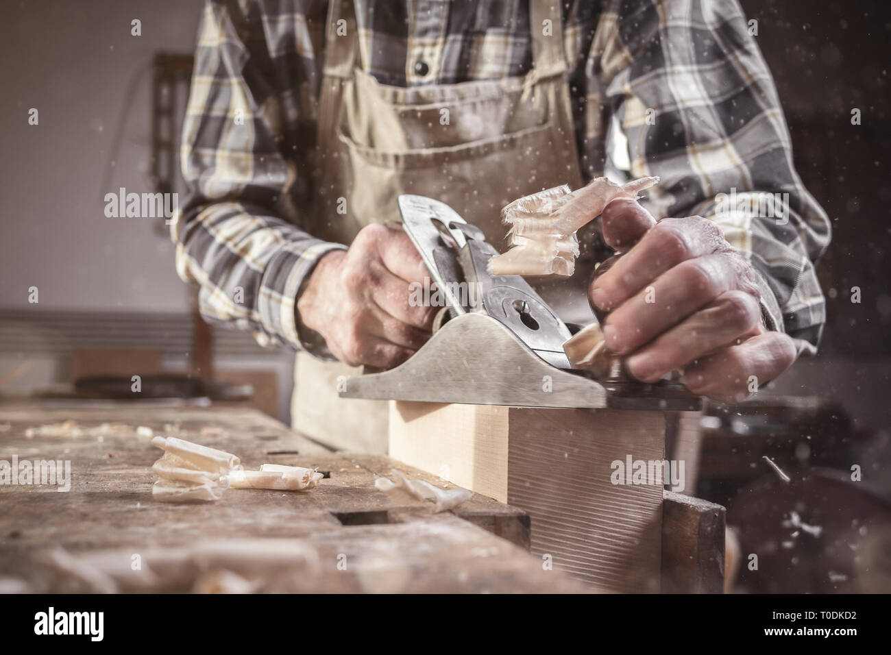 Le braccia e le mani di un falegname lavora con una ruspa utensile in un workshop polverosi Foto Stock