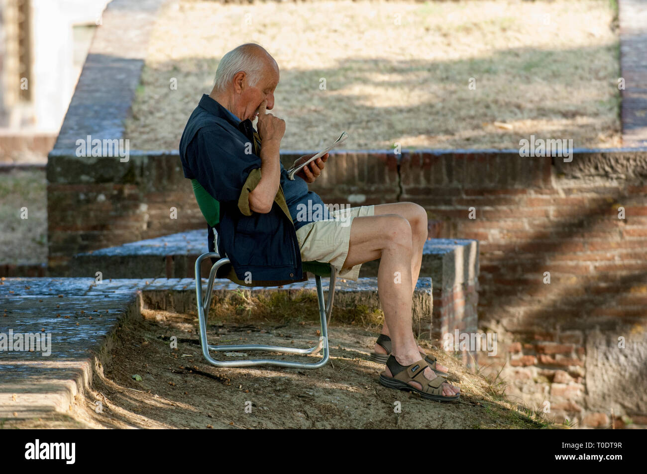 Un uomo è seduto e la lettura nel parco, Lucca, Italia. Foto Stock