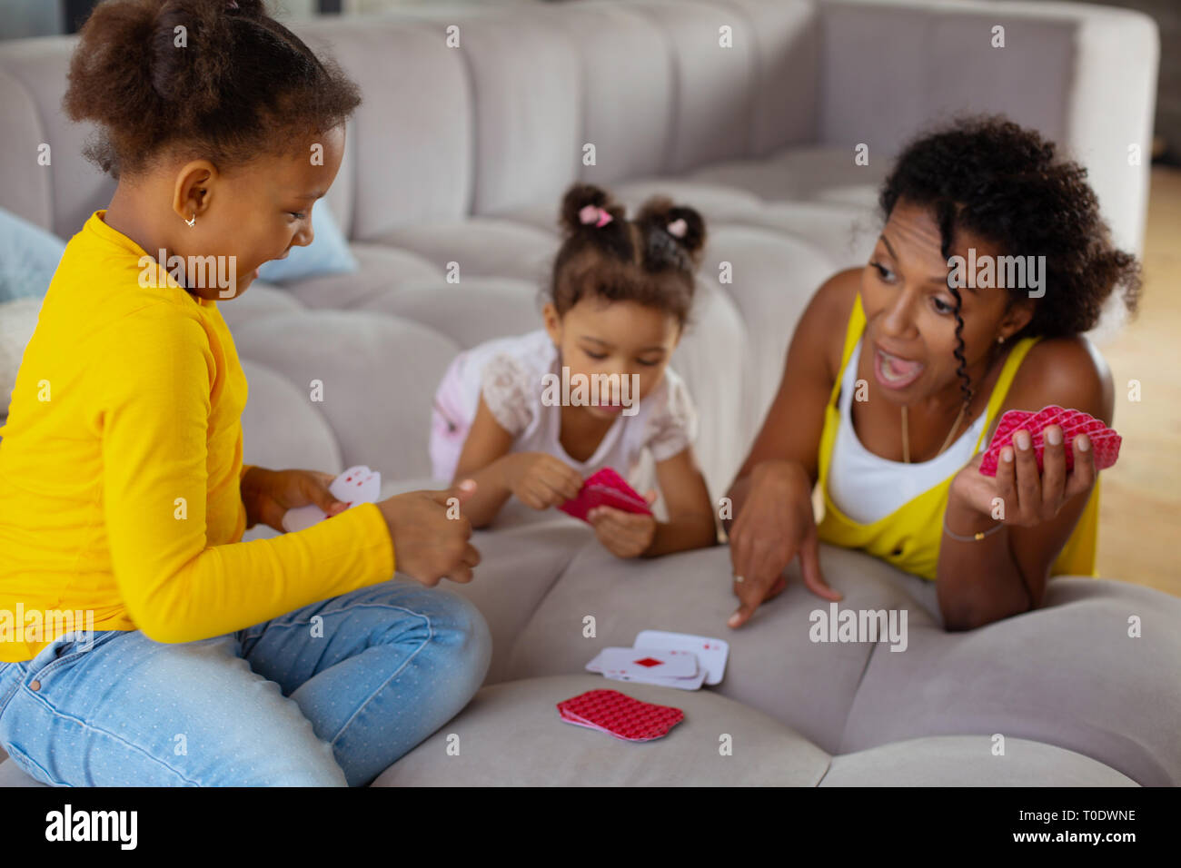 Positive le ragazze felici giocando a carte con la mamma Foto Stock
