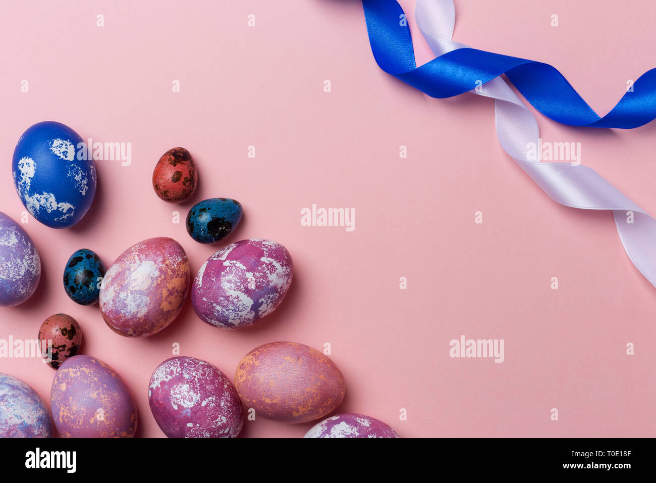 Gioioso della Pasqua uova colorate di bianco e blu con nastro su sfondo rosa. Spazio per il testo, concetto di sfondo di Pasqua Foto Stock