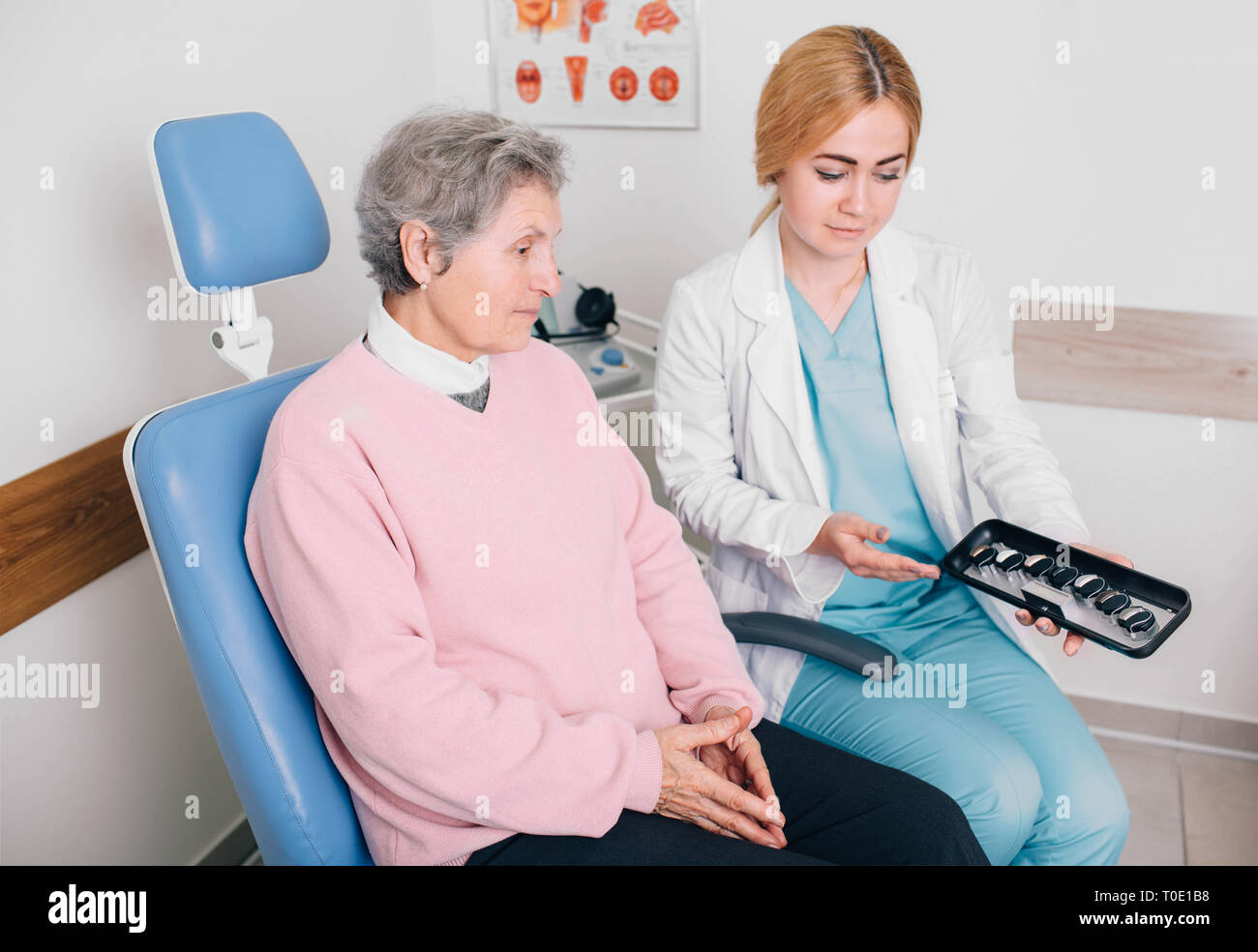 Medico aiuta un paziente anziano la scelta di un apparecchio acustico. Udito il trattamento con apparecchi acustici Foto Stock