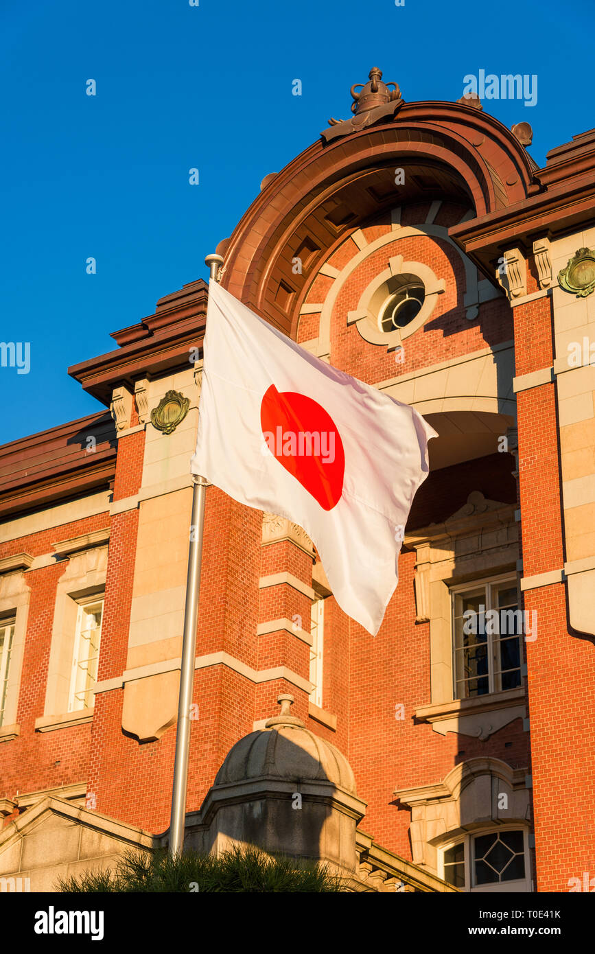 La stazione di Tokyo vecchia facciata in mattoni con il Giappone Nazione bandiera sventola davanti ad esso Foto Stock