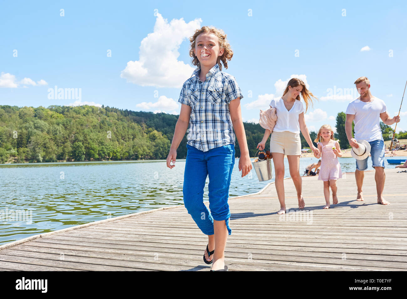 La famiglia felice con bambini fa una passeggiata sulla riva del lago in estate Foto Stock