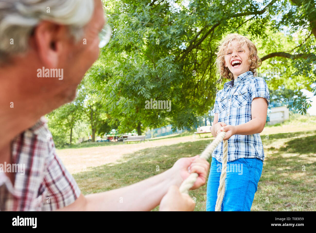 Ridendo boy in tiro della fune la concorrenza nel parco in estate con il nonno Foto Stock