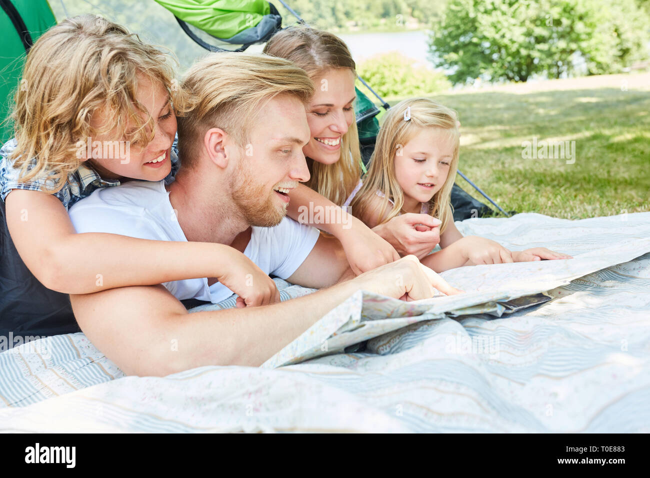 Famiglia con due bambini in tenda sono alla ricerca di una mappa sulla vacanza in campeggio Foto Stock