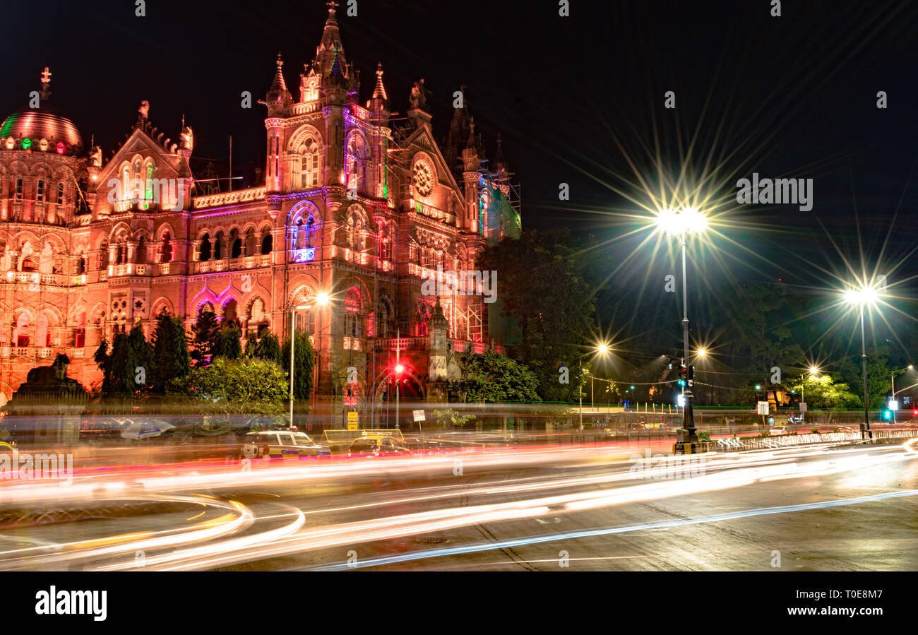 Bellissimo Victoria Terminus aka Chhatrapati Shivaji Maharaj Terminus durante la tarda notte, con sentieri di luce del veloce il traffico in movimento e le luci di strada Foto Stock