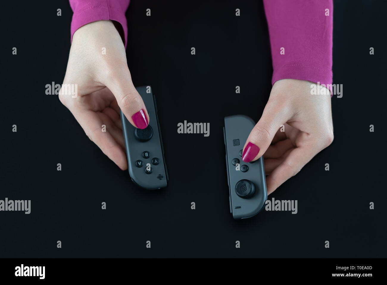 HEGGENES - 14 febbraio: vista dall'alto di donna mani interruttore Nintendo controller di gioco per la riproduzione di video digitali isolati giochi su nero Foto Stock