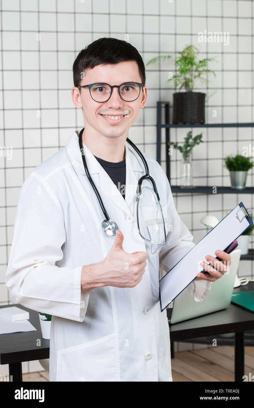 Assistenza sanitaria, la professione e il concetto di medicina - sorridente medico maschio che mostra i pollici fino oltre il medico lo sfondo di office Foto Stock