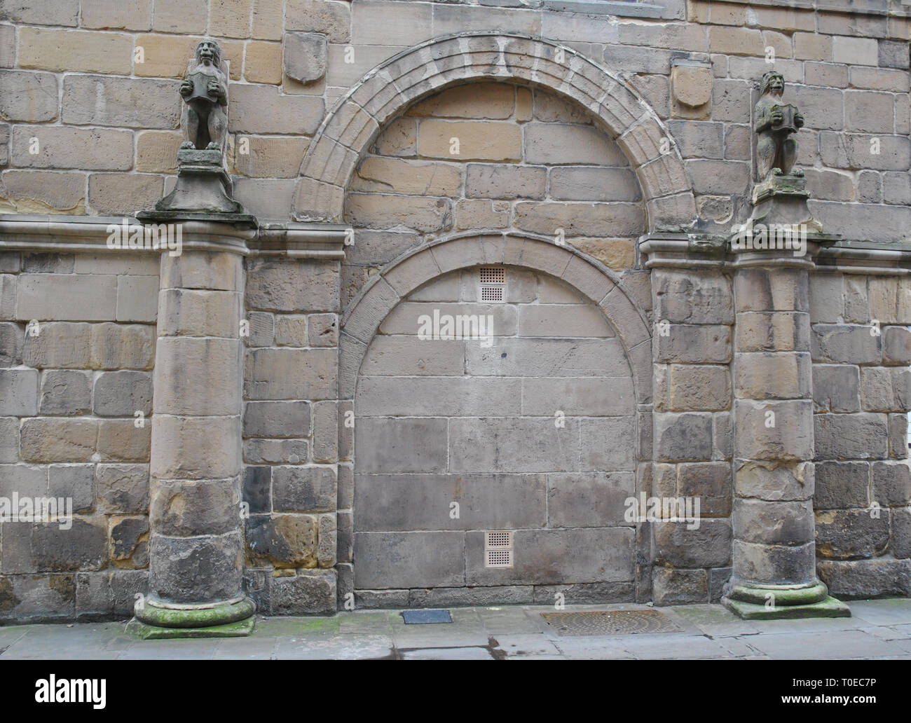 Una murata vecchio portale in un edificio medievale che mostra colonna e gargoyle dettaglio Foto Stock