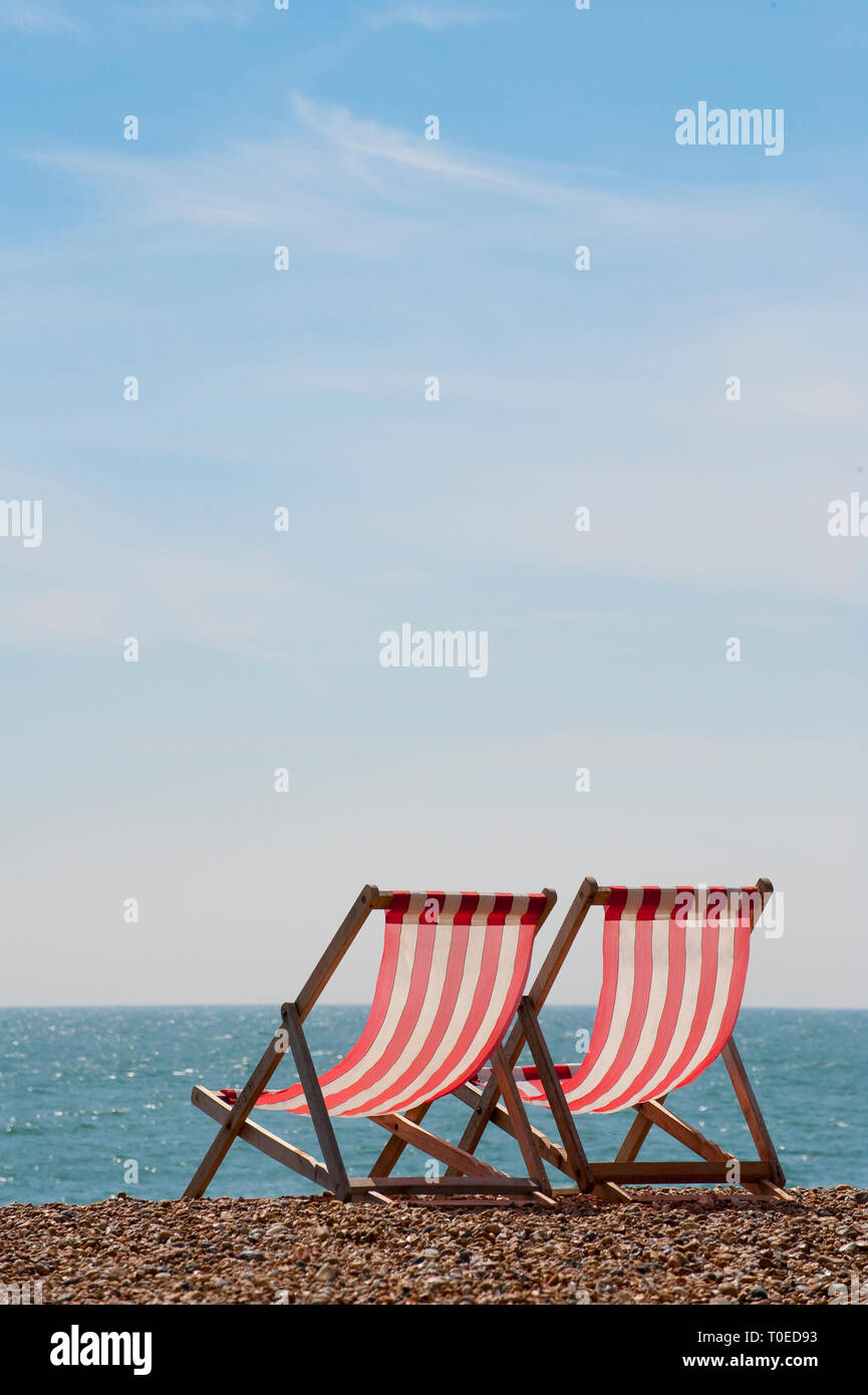 Coppia di legno tradizionali sedie a sdraio sulla spiaggia di Brighton, Sussex, Inghilterra. Foto Stock