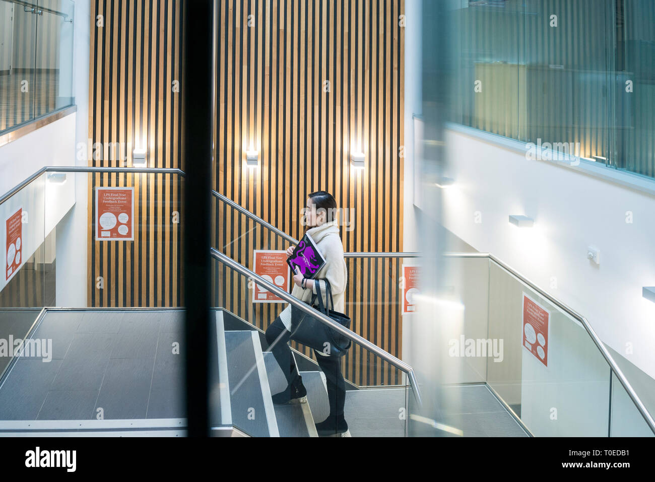 Una femmina di studenti asiatici passeggiate attraverso le diverse aree comuni all'interno di un edificio universitario Foto Stock