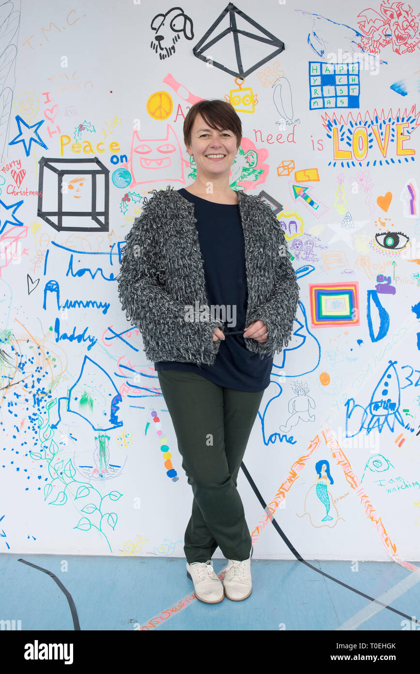 Una foto di un amichevole tipo caring donna in piedi nella sala della galleria di Phoenix in Brighton davanti a una parete in cui i bambini hanno disegnato su. Foto Stock