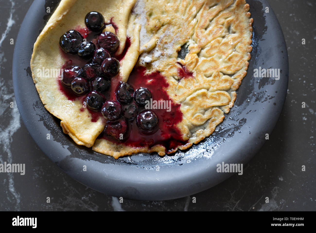 La salsa di mirtilli su una crêpe / pancake, su una piastra nera Foto Stock
