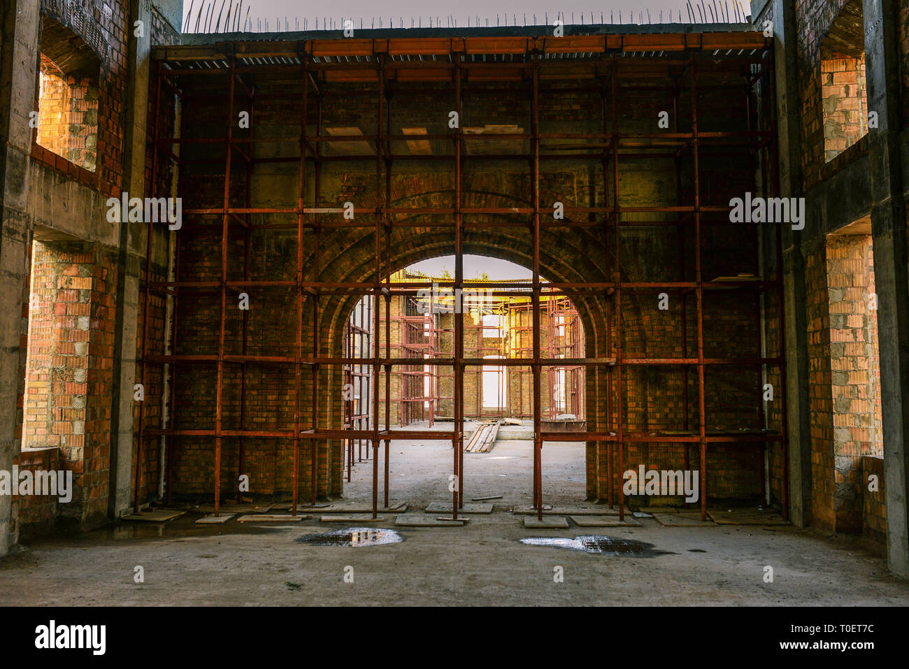 La costruzione dell'edificio. Grande Arco di mattoni. Costruzione di ponteggi su una casa in costruzione. Pavimento in calcestruzzo Foto Stock