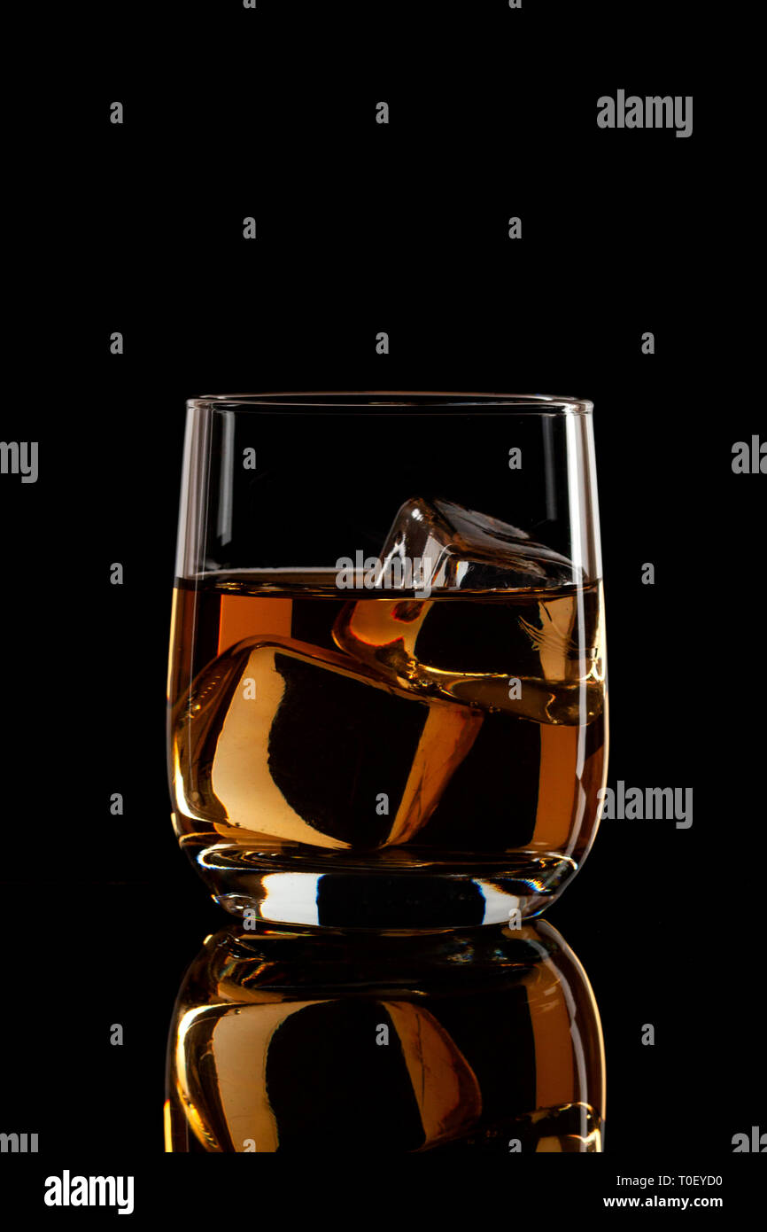 Il Brandy con pezzi di ghiaccio su sfondo nero Foto Stock