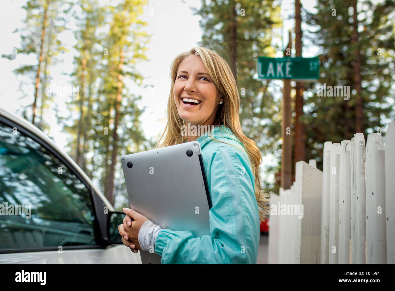 Sorridente giovane donna che porta il suo computer portatile. Foto Stock