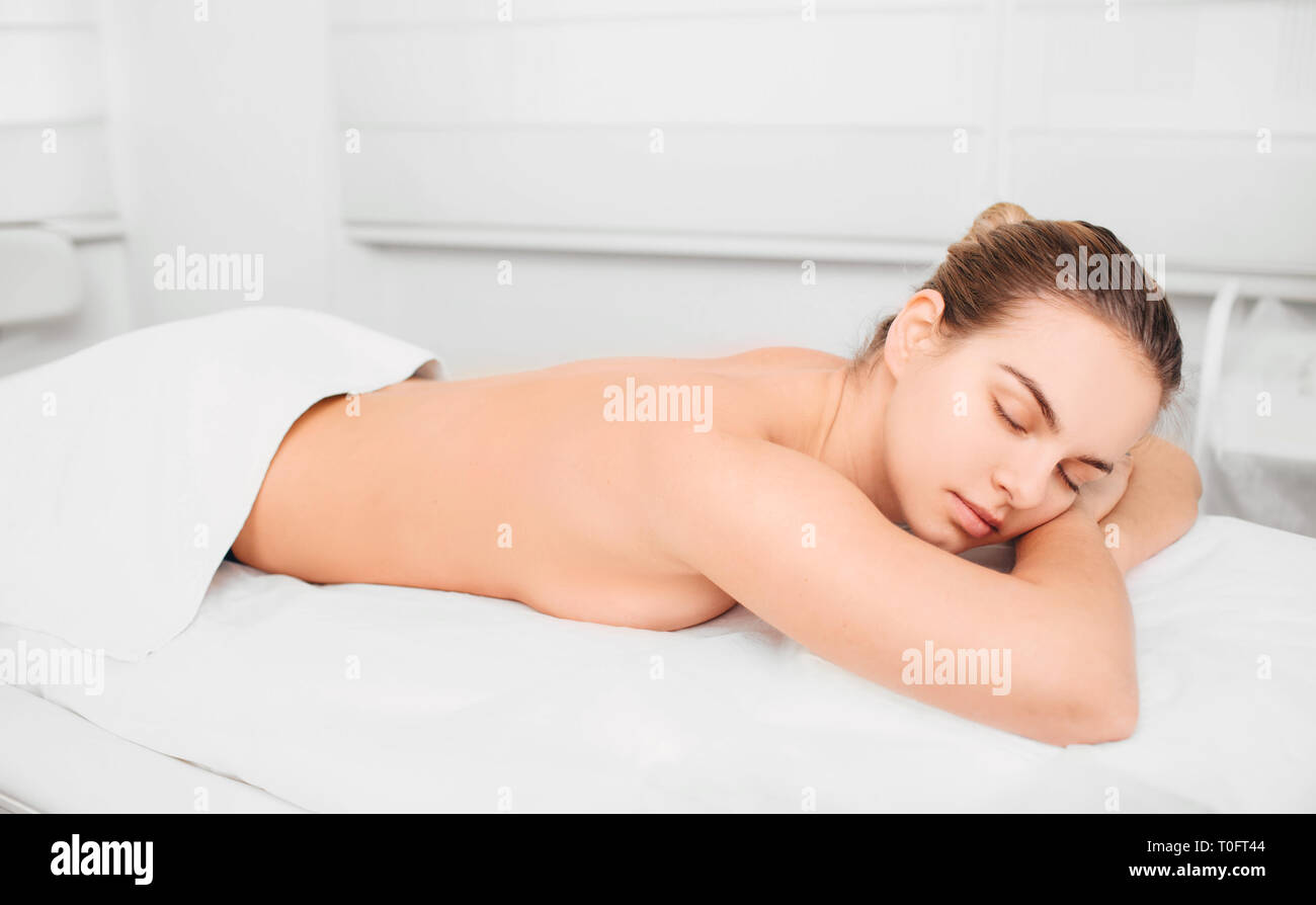Rilassata donna sdraiata su asciugamano a spa Foto Stock