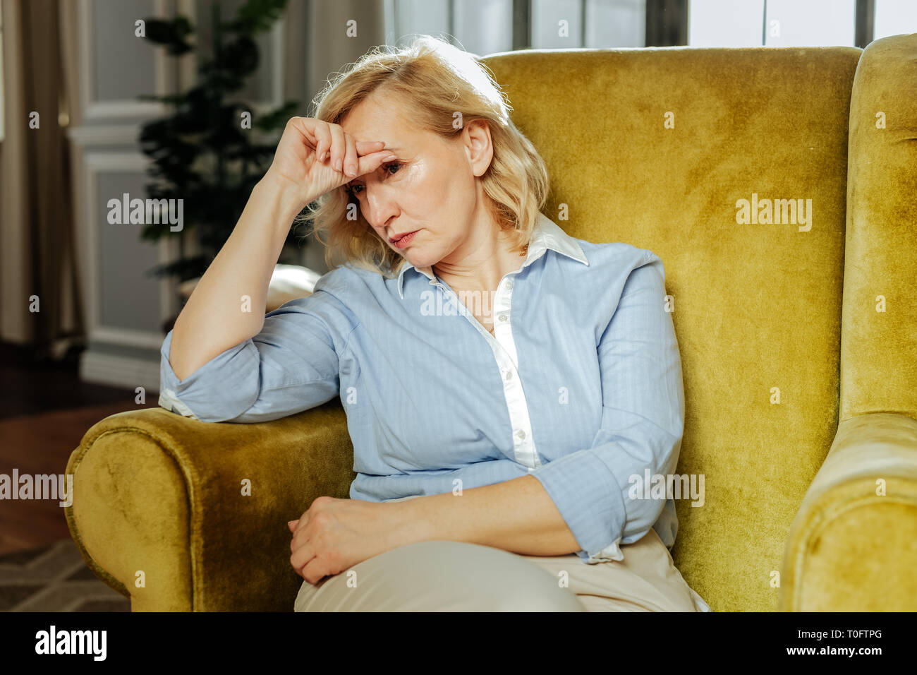 Sconvolto donna adulta appoggiata sulla sua mano mentre si riposa in cattedra Foto Stock