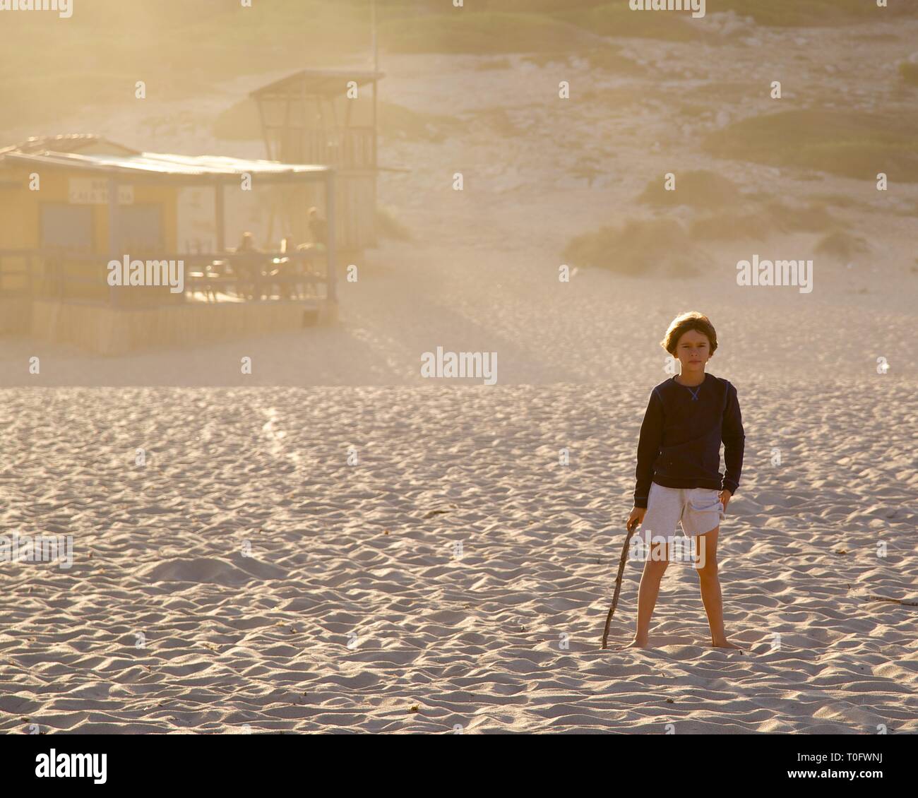 Ragazzo giovane nella parte anteriore della rustica capanna sulla spiaggia di Cala Torta, Mallorca al tramonto Foto Stock