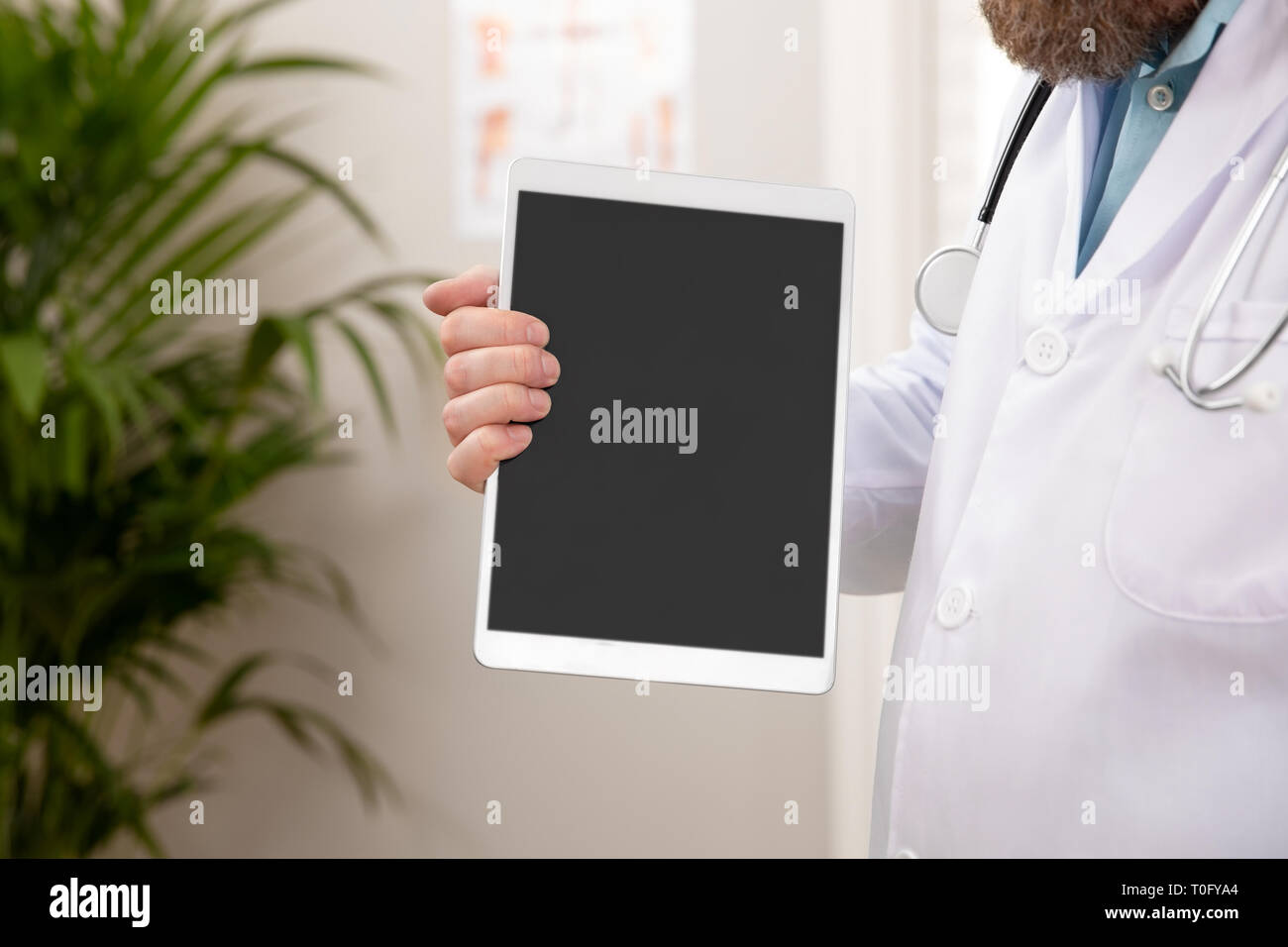 Maschio adulto medico che mostra un'immagine digitale o una relazione su una tavoletta grafica Foto Stock