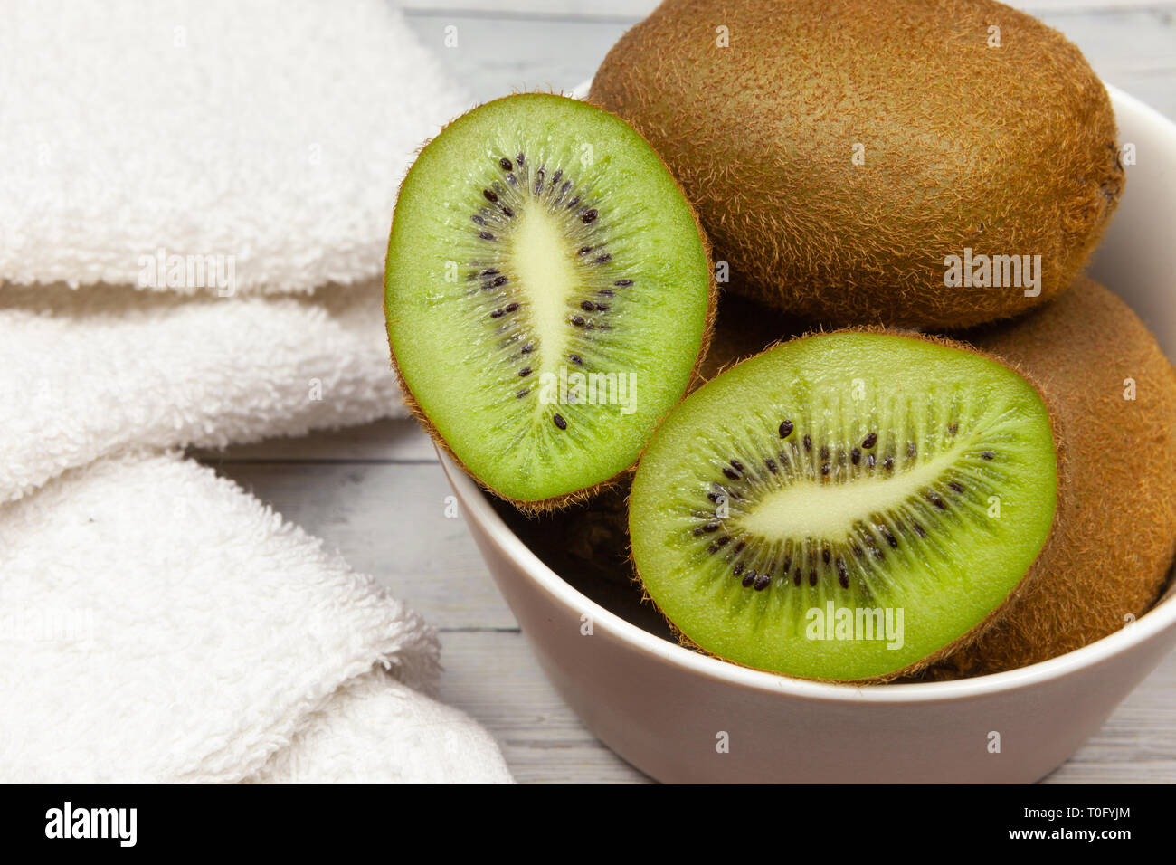 Kiwi le fette su un tavolo di legno accanto ad un asciugamano bianco, close-up Foto Stock
