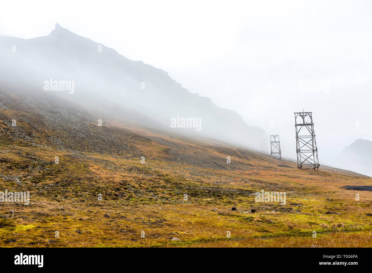 Vecchia miniera di carbone tranportation pilastro, foschia mattutina a Longyearbyen, Svalbard, Norvegia Foto Stock