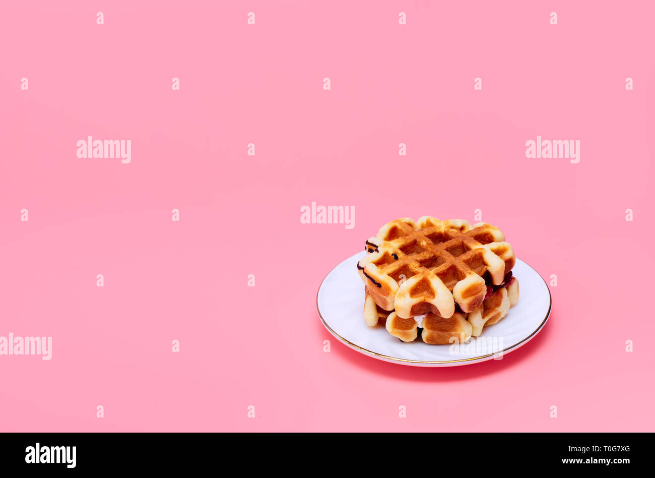 Waffles fatti in casa su un sfondo rosa. Una gustosa prima colazione. In casa la cottura. Minimalismo. Foto Stock