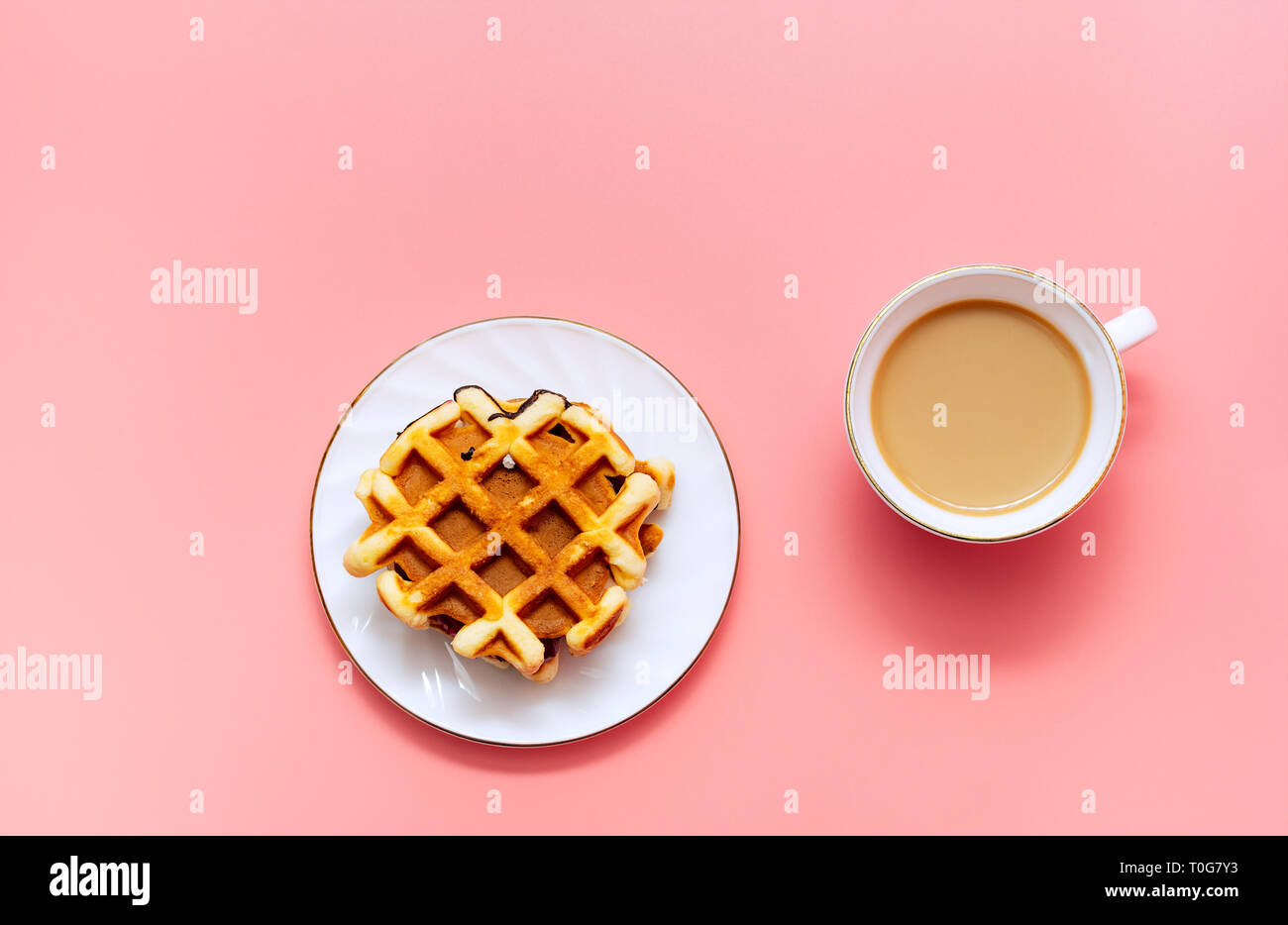 Una tazza di caffè con latte e waffles fatti in casa su un sfondo rosa. Una gustosa prima colazione. Minimalismo. Foto Stock