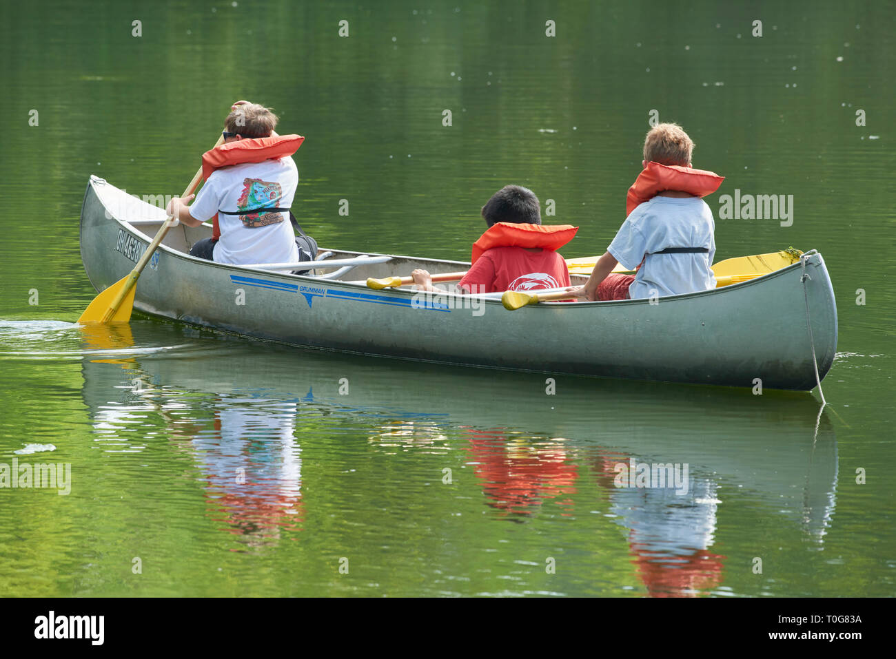 Tre ragazzi in summer camp di canoa kayak intorno al laghetto Foto Stock