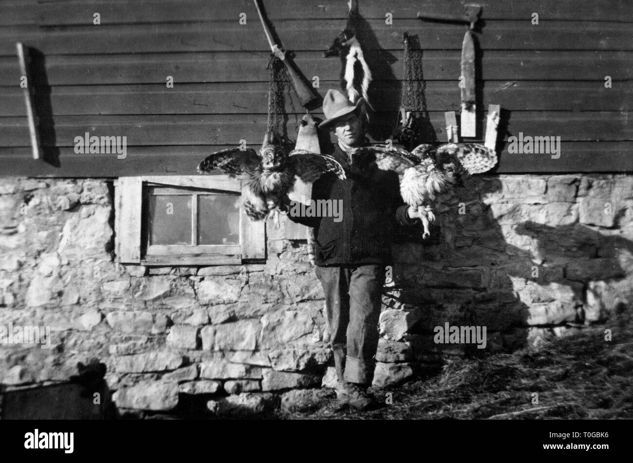 Un cacciatore pone con due owl e alcune pelli animali, ca. 1930. Foto Stock