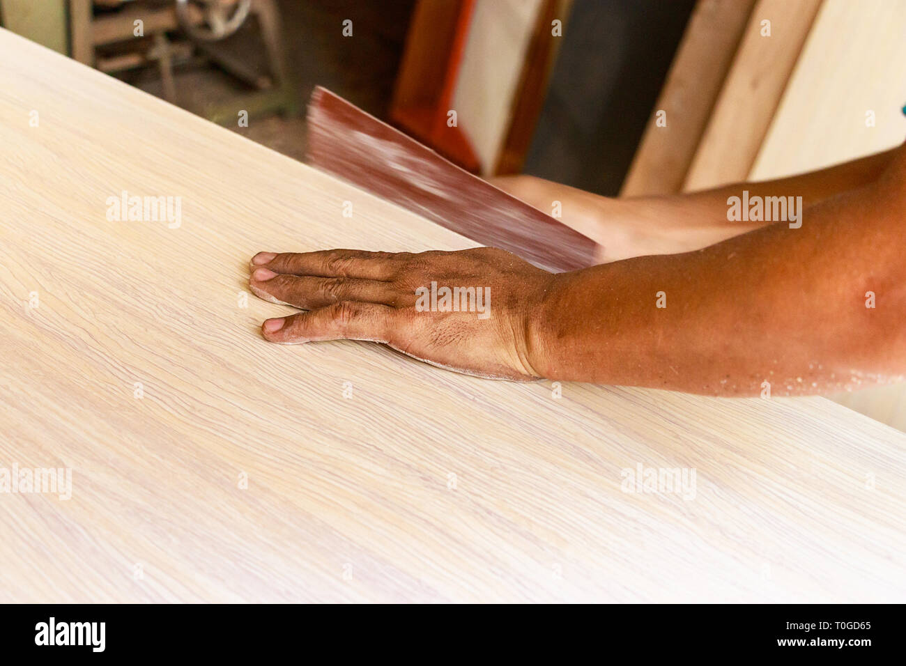 Falegname maschio mani la levigatura del bordo di un tavolo manualmente, all'interno. Foto Stock