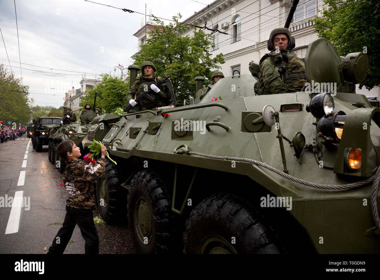 Un ragazzo lancia fiori al russo corazzato trasporto di personale BTR-80 durante la parata militare nelle vie centrali della città di Sebastopoli, Crimea 9 di Maggio Foto Stock