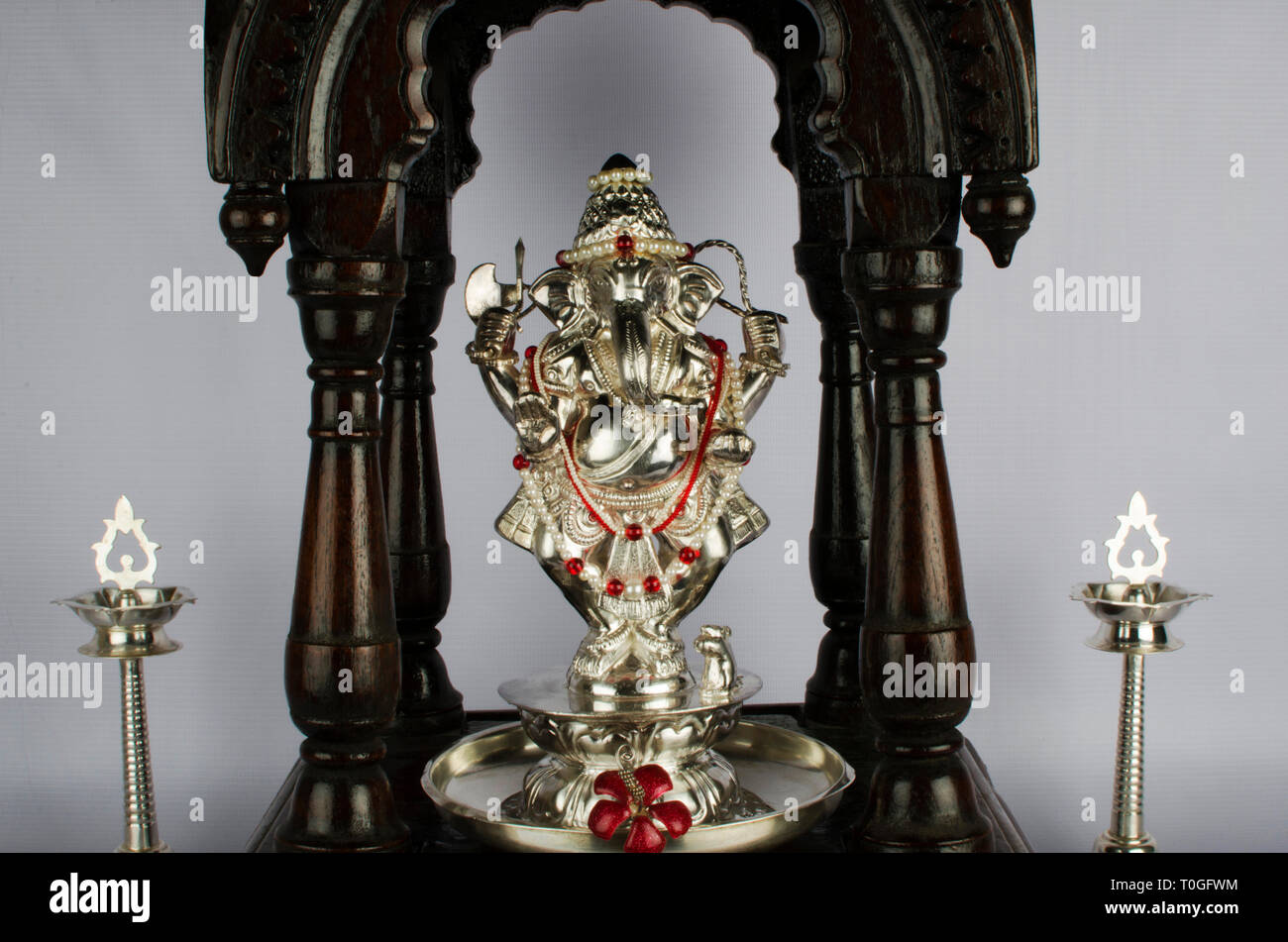Argento Signore Ganesh idolo collocato in un tradizionale botte di antiquariato Maharashtrian devara o Puja camera o cappella e due tradizionali Samai indiano o lampade k Foto Stock