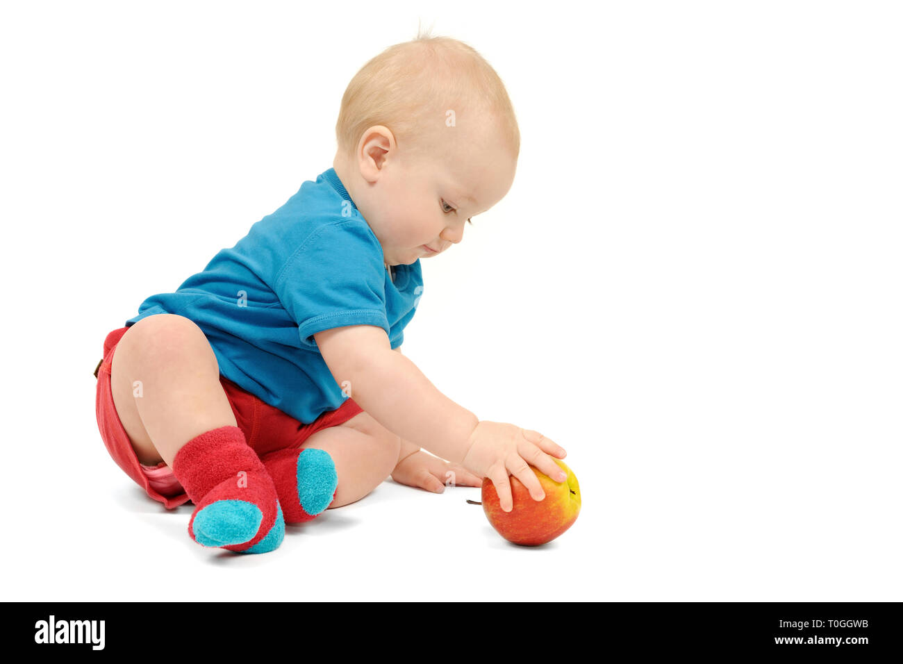 Ragazzino con un Apple seduto su sfondo bianco, isolato Foto Stock