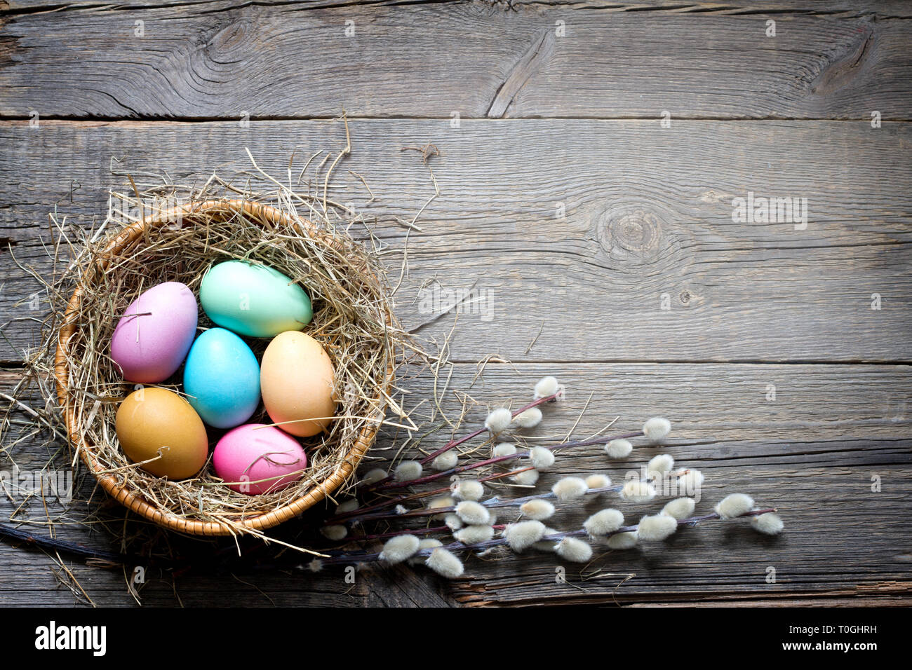 Pasqua uova colorate nel nido con fiori su vintage di tavole di legno e lo spazio vuoto Foto Stock