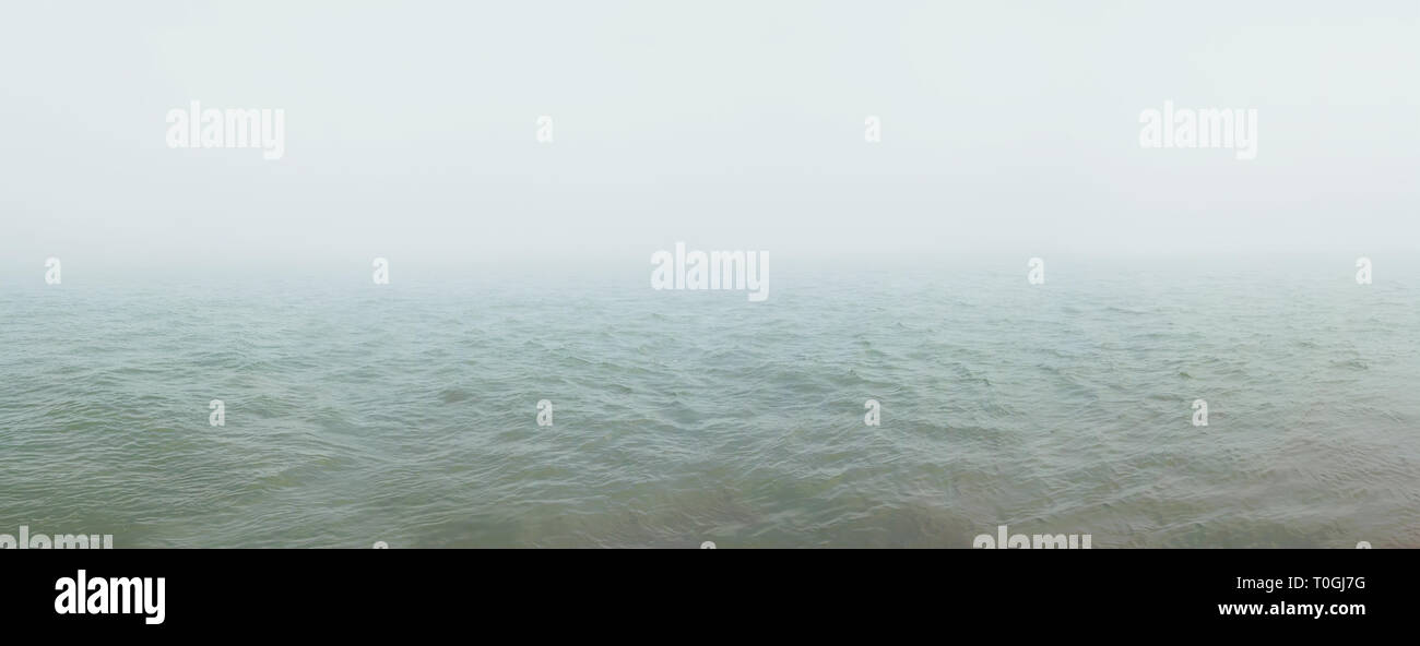 Una fitta nebbia si diffonde oltre il fiume. Sfondo naturale Foto Stock