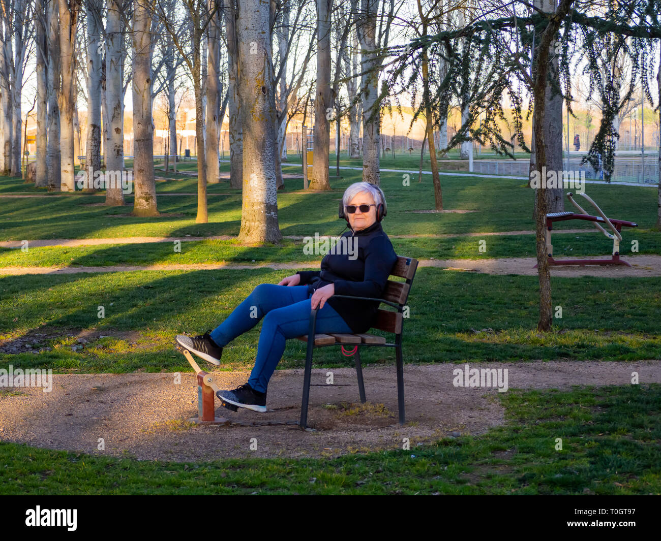 Un senior donna con i capelli bianchi praticare ginnastica in un bio-sana park Foto Stock