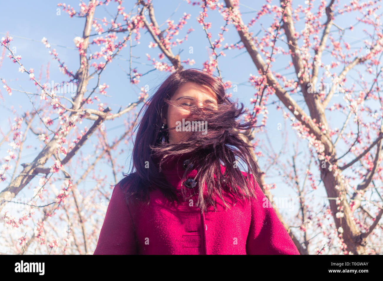Felice ragazza sta ballando tra fiori di ciliegio Foto Stock