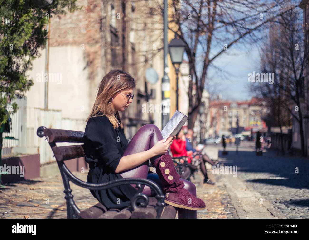Giovane bella moda donna leggendo un libro in un ambiente di tradizionale architettura urbana Foto Stock