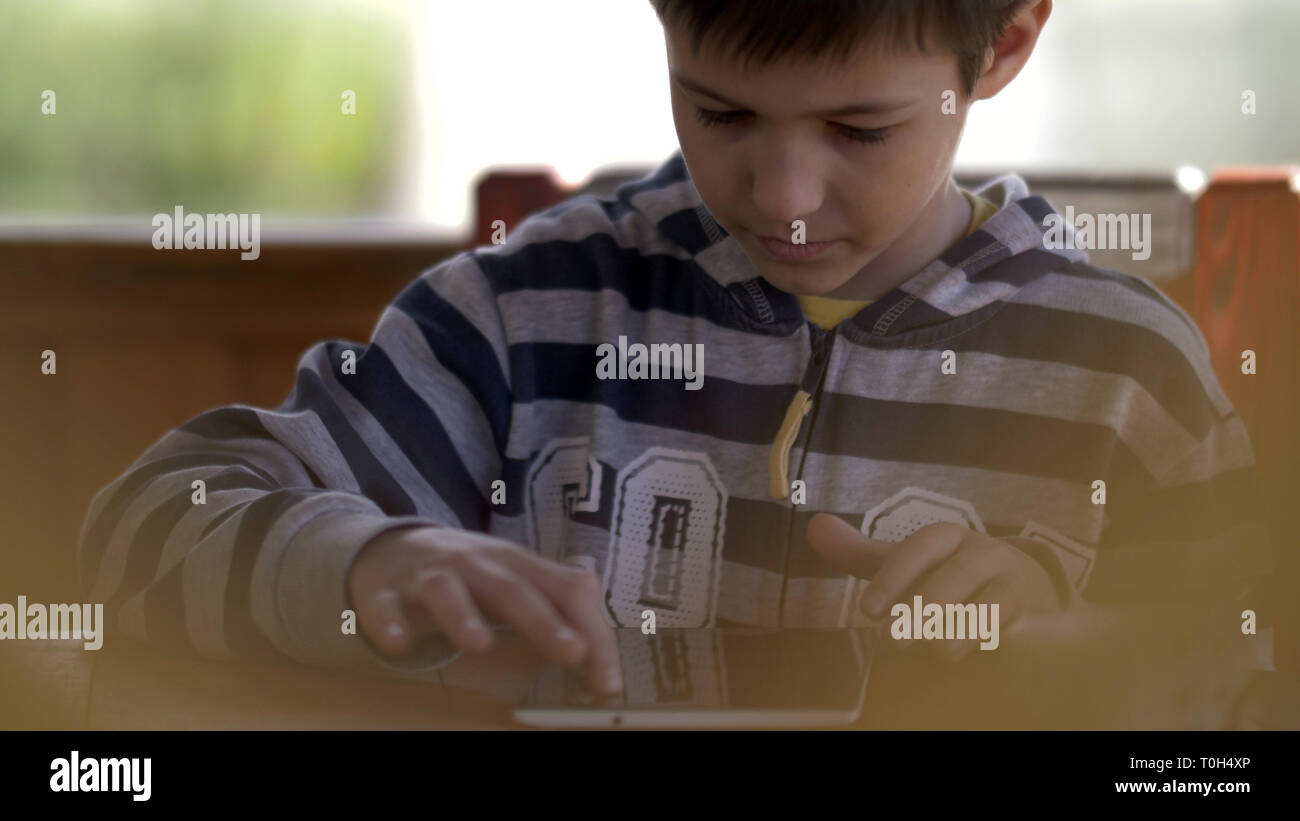 Ragazzo gioca con interesse sulla tavoletta, divertirsi Foto Stock