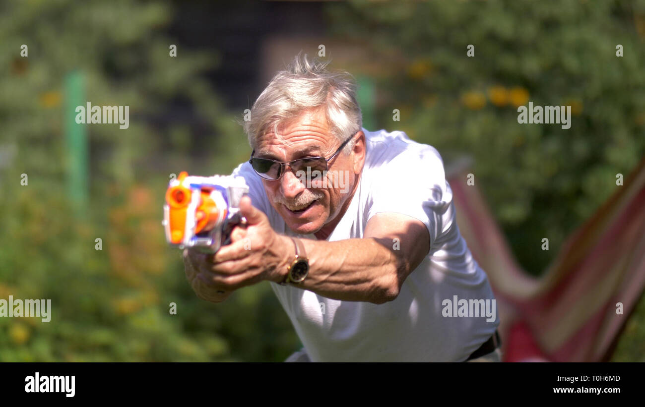 Senior uomo con pistola giocattolo lotta sulla natura Foto Stock