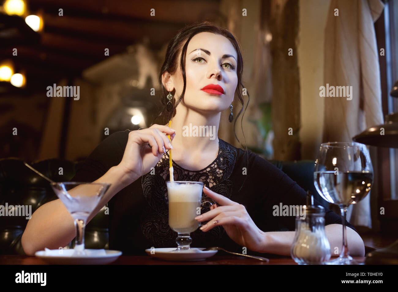 La donna a una tabella in un bar a bere caffè. Foto Stock