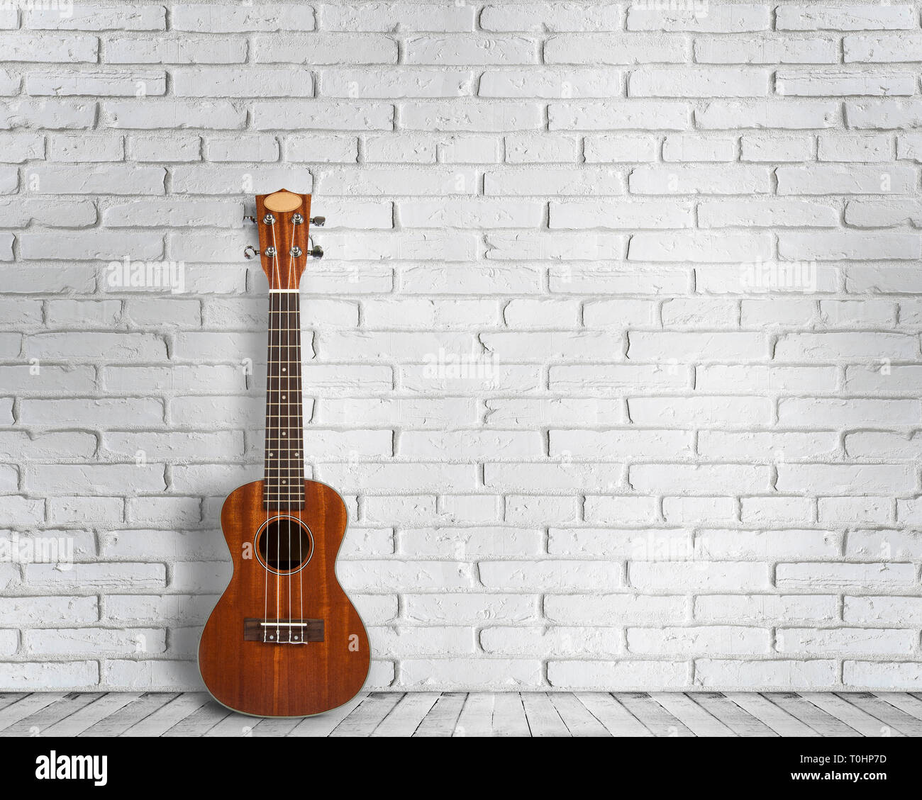 Ukulele chitarra su un muro bianco sullo sfondo. Concetto di viaggio e di stile di vita. Foto Stock