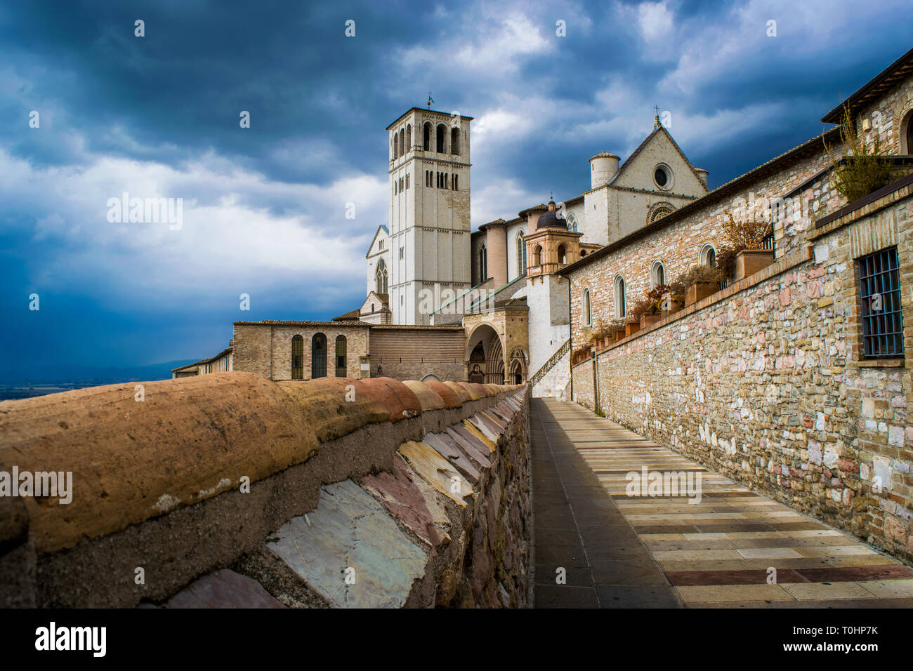Il paesaggio della città medievale di Assisi in Italia, con l'antico villaggio storico e la Basilica di San Francesco con la torre campanaria sotto un Foto Stock